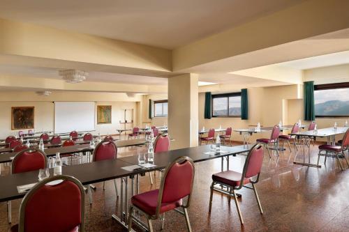 a conference room with tables and red chairs at Renaissance Tuscany Il Ciocco Resort & Spa in Barga