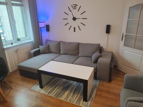 a living room with a couch and a clock on the wall at Apartament Mickiewicza w centrum Augustowa in Augustów