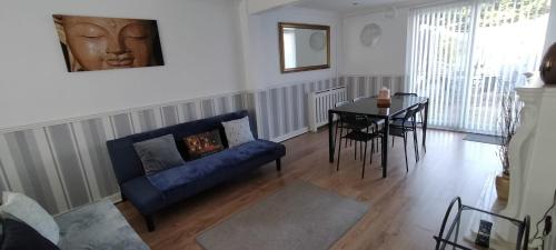 a living room with a blue couch and a table at Ladbury House in Walsall near M6, Walsall Uni and Hospital, with free parking and easy access to Birmingham city centre and West Bromwich, only 20 mins to NEC and Birmingham airport, 15 mins to Villa Park, Great for contractors! in Bescot