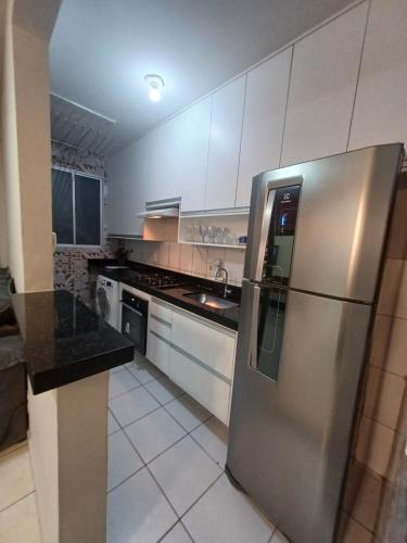 a stainless steel refrigerator in a kitchen with white cabinets at Apartamento com AR Condicionado, Condomínio aconchegante com piscina 2 Qts in Serra