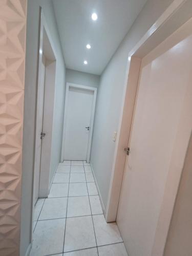 a hallway with white walls and a white door at Apartamento com AR Condicionado, Condomínio aconchegante com piscina 2 Qts in Serra