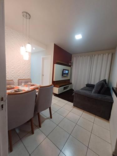 a living room with a dining table and a couch at Apartamento com AR Condicionado, Condomínio aconchegante com piscina 2 Qts in Serra