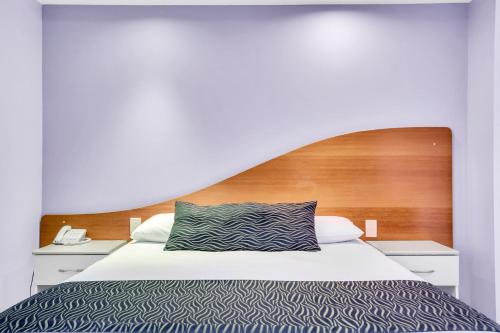a bedroom with a bed with a wooden headboard at Shellharbour Village Motel in Shellharbour