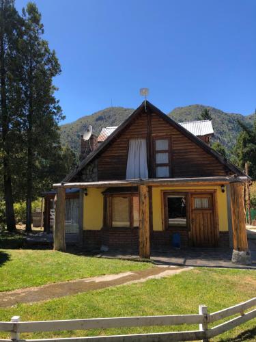 uma casa de madeira com uma cerca em frente em Cabañas franlu em Lago Puelo