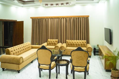 sala de estar con sofás, mesa y sillas en COMFORT HOME, en Gujrāt