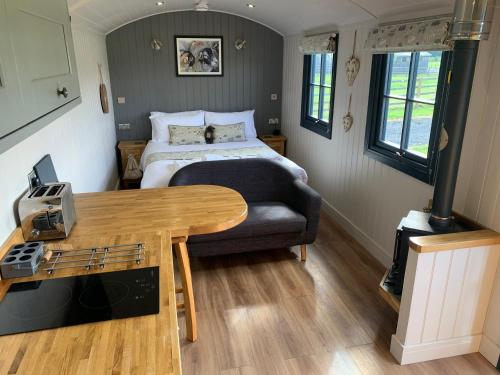 a small bedroom with a bed and a table at Springwood Shepherd Huts Glamping York in York