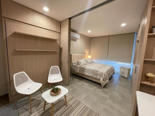 a bedroom with a bed and two white chairs at Aparta estudio tipo suit , nuevo , dotado en Playa Salguero in Santa Marta