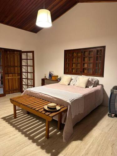 a bedroom with a large bed and a table at Casa Pedra da Lua, uma casa para contemplar o agreste. in Gravatá