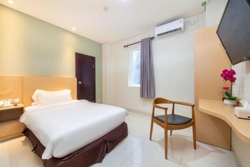 a bedroom with a bed and a desk and a chair at Life Hotel Soekarno Hatta Makassar in Makassar