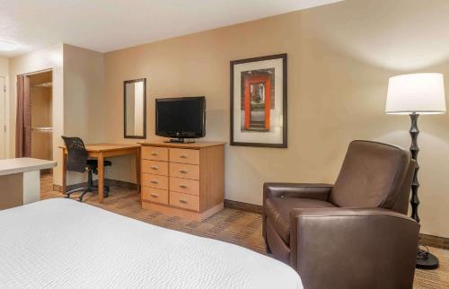 a hotel room with a bed and a desk with a television at Studio 6 Extended Stay - St Louis, MO - Westport Craig Road in Maryland Heights