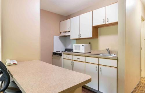a small kitchen with white cabinets and a sink at Studio 6 Extended Stay - St Louis, MO - Westport Craig Road in Maryland Heights
