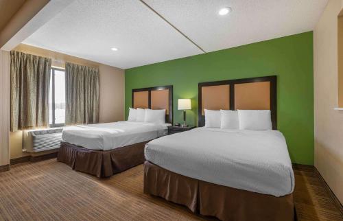 Extended Stay America Select Suites - Cincinnati - Florence - Meijer Dr في فلورنس: سريرين في غرفة فندق بجدران خضراء