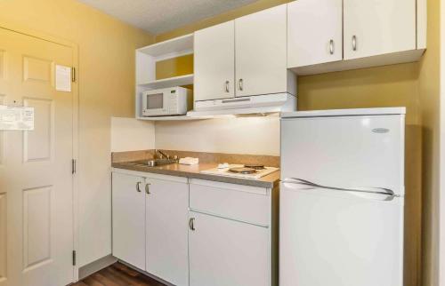 a kitchen with white cabinets and a white refrigerator at Extended Stay America Select Suites - Chesapeake - Churchland Blvd in Chesapeake