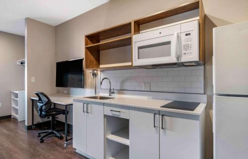 a kitchen with a sink and a desk with a microwave at Extended Stay America Premier Suites - Tampa - Gibsonton - Riverview in Gibsonton