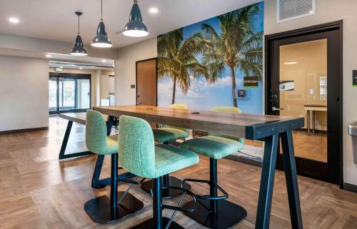 Extended Stay America Premier Suites - Tampa - Fairgrounds - Casino في تامبا: غرفة طعام مع طاولة خشبية كبيرة مع كراسي خضراء