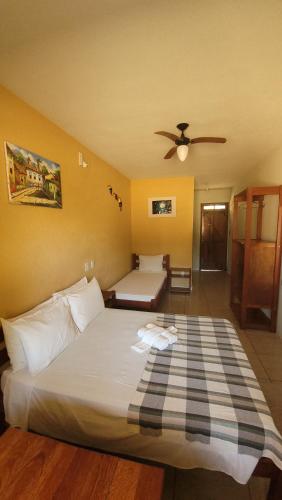 a bedroom with a large white bed with a ceiling fan at Pousada Tropicalia in Itaparica Town