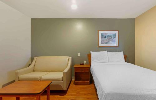 Habitación de hotel con cama y silla en Extended Stay America Select Suites - Kansas City - Stadium en Independence