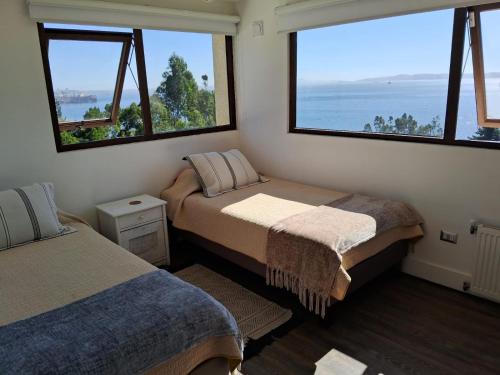 2 camas en una habitación con ventanas grandes en VILLA THE SUN, en Concepción