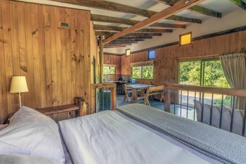 1 dormitorio con 1 cama en una habitación con paredes de madera en Cabañas Pucon Location, en Pucón