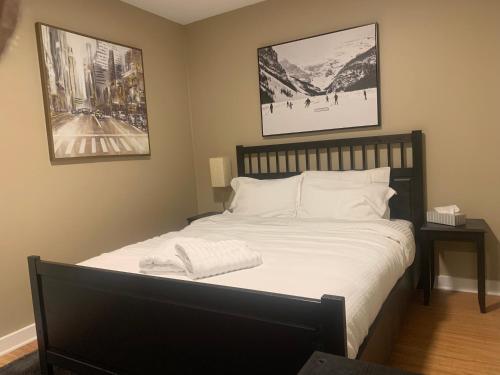 sypialnia z łóżkiem z białą pościelą i dwoma zdjęciami w obiekcie Where eagles fly w mieście West Vancouver