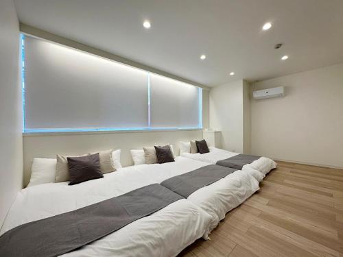 ein großes Bett in einem Zimmer mit einem großen Fenster in der Unterkunft bHOTEL Nikke - Spacious Apt for 12Ppl Very Good Location in Ōsukachō
