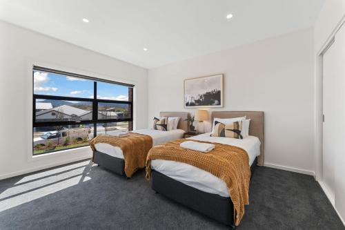 Un dormitorio con dos camas y una gran ventana. en 1B Alpine View Retreat - 4BR Luxurious Escape l Mountain Views l Fast WiFi, en Jindabyne