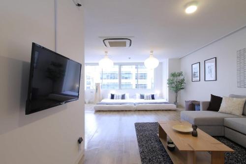 a living room with a couch and a tv on a wall at b hotel Nikke - 2BR Apt for 10ppl near Hondori Shopping in Hiroshima