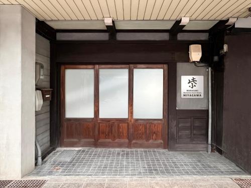 Una puerta a un edificio con un cartel. en Hostel Miyagawa by Murasaki Ryokan, en Takayama