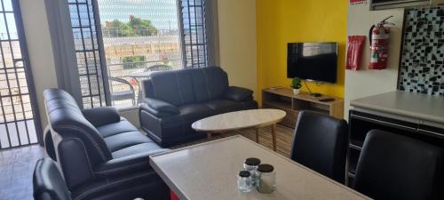 a living room with chairs and a table and a tv at ZEG in Suva