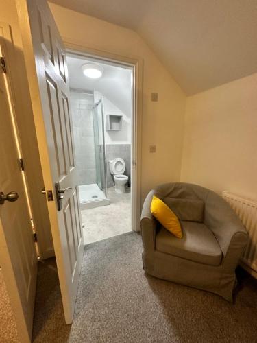 a room with a chair and a bathroom with a toilet at Modern en-suite spacious room near Deansgate manchester city in Manchester