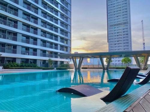 een zwembad met 2 stoelen en een gebouw bij SMDC Fame Residence luxurious family suite condo near mrt in Manilla