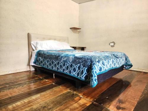 a bedroom with a bed with a blue blanket on it at El refugio de los viajeros in Quito
