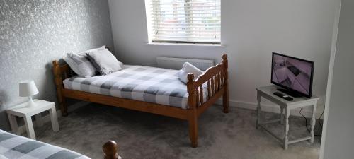 a small bedroom with a bed and a television at St Martins House Birmingham Near NEC, Jaguar Land Rover, HS2, Resorts World, Bear Grylls Centre and Birmingham Airport, with garage and free parking, perfect for contractors and families in Kingshurst