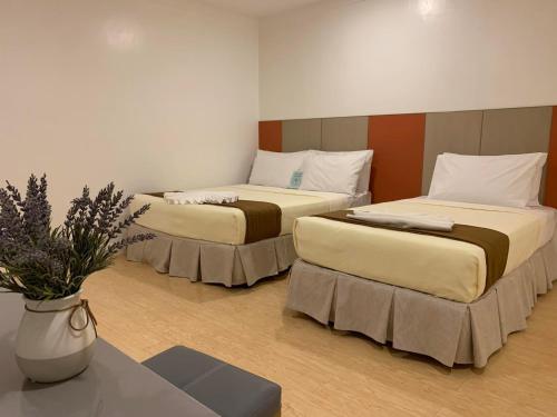 two beds in a room with a vase of flowers at ILOILO GRAND HOTEL in Iloilo City