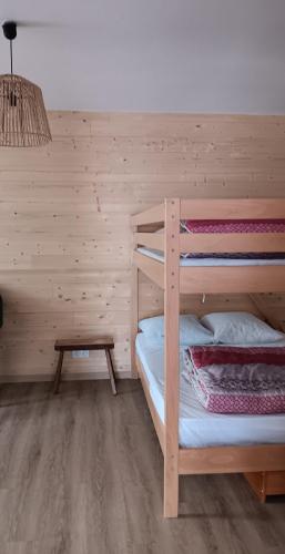 une chambre avec deux lits superposés et une table dans l'établissement MAISON OSSATURE BOIS, à La Bourboule