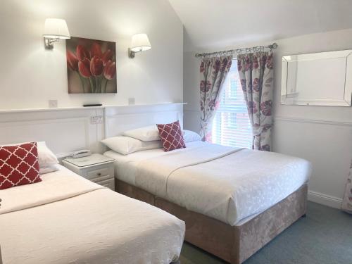 1 dormitorio con 2 camas y una ventana con tulipanes rojos en Dergvale Hotel, en Dublín