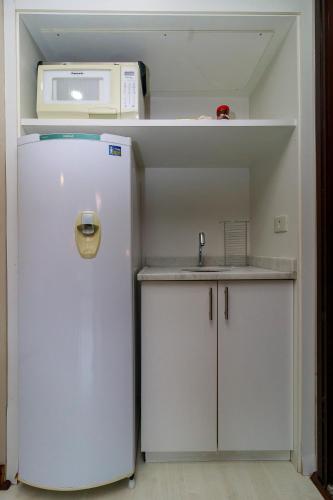a small kitchen with a refrigerator and a microwave at Flat Executivo Verbo Divino in Sao Paulo
