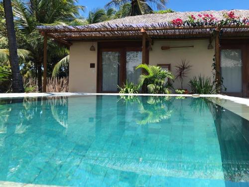 a villa with a swimming pool in front of a house at Casa Rosa Atins in Atins