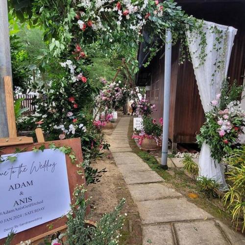 een loopbrug met bloemen en een bord in een tuin bij Rumah Melati@Zaki’s Residence, Marang, Terengganu in Kampong Ru Lima