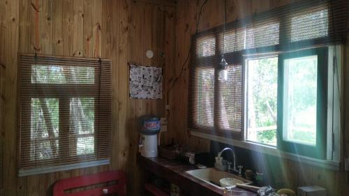 ein Badezimmer mit Holzwänden, einem Waschbecken und 2 Fenstern in der Unterkunft Luna Vieja in Tigre