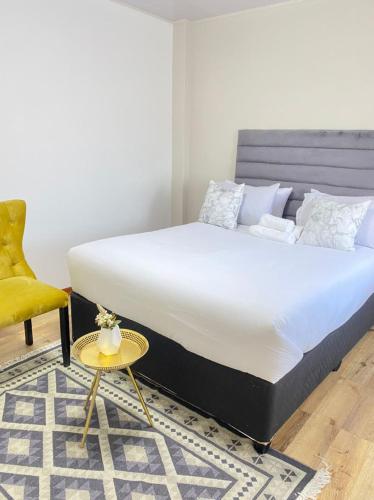 a bedroom with a large bed and a yellow chair at Stylish apartments in Gaborone