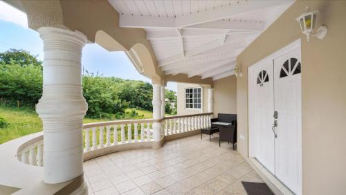 a large porch with a white ceiling and columns at Kaibus Place- Quaint Quiet and Cosy in Morne Rouge