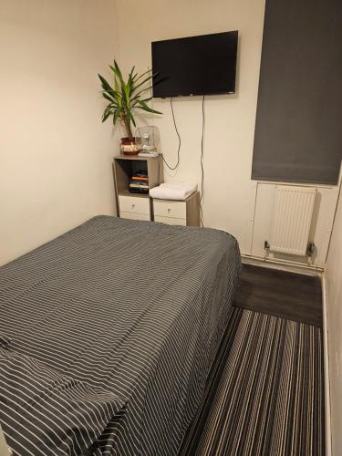 um quarto com uma cama e uma televisão de ecrã plano em single room close to the city em Londres
