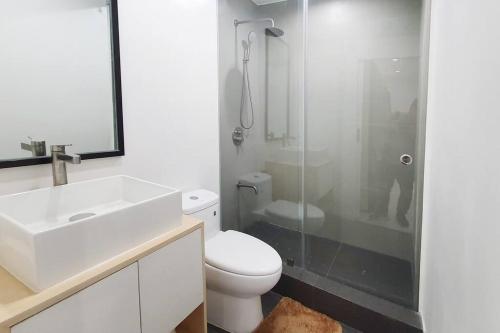 a bathroom with a toilet and a sink and a shower at Travelers Inn - Cozy Capsule Bunks, Makati in Manila