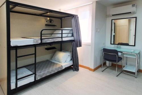 Habitación con 2 literas, escritorio y espejo. en Travelers Inn - Cozy Capsule Bunks, Makati, en Manila
