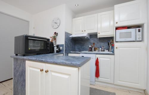 La cuisine est équipée de placards blancs et d'un four micro-ondes noir. dans l'établissement Nice Apartment In Mandelieu-La-Napoule, à Mandelieu-la-Napoule