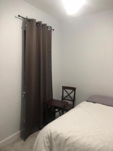 a bedroom with a bed and a chair and curtains at Single room in willesden in London