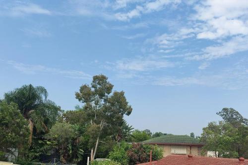 a house with trees and a blue sky at Short-long term Private Smart modern studio in Jamboree Heights