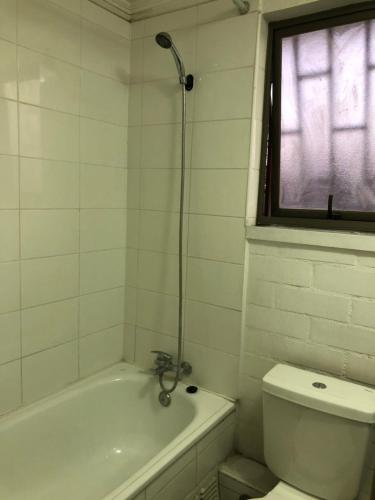 a white bathroom with a tub and a toilet at Tu espacio Re - Cuarto con encanto in Santiago