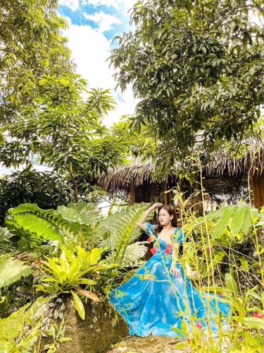 a woman in a blue dress in front of a house at Pu Luong Cuisine Garden Homestay in Làng Bang